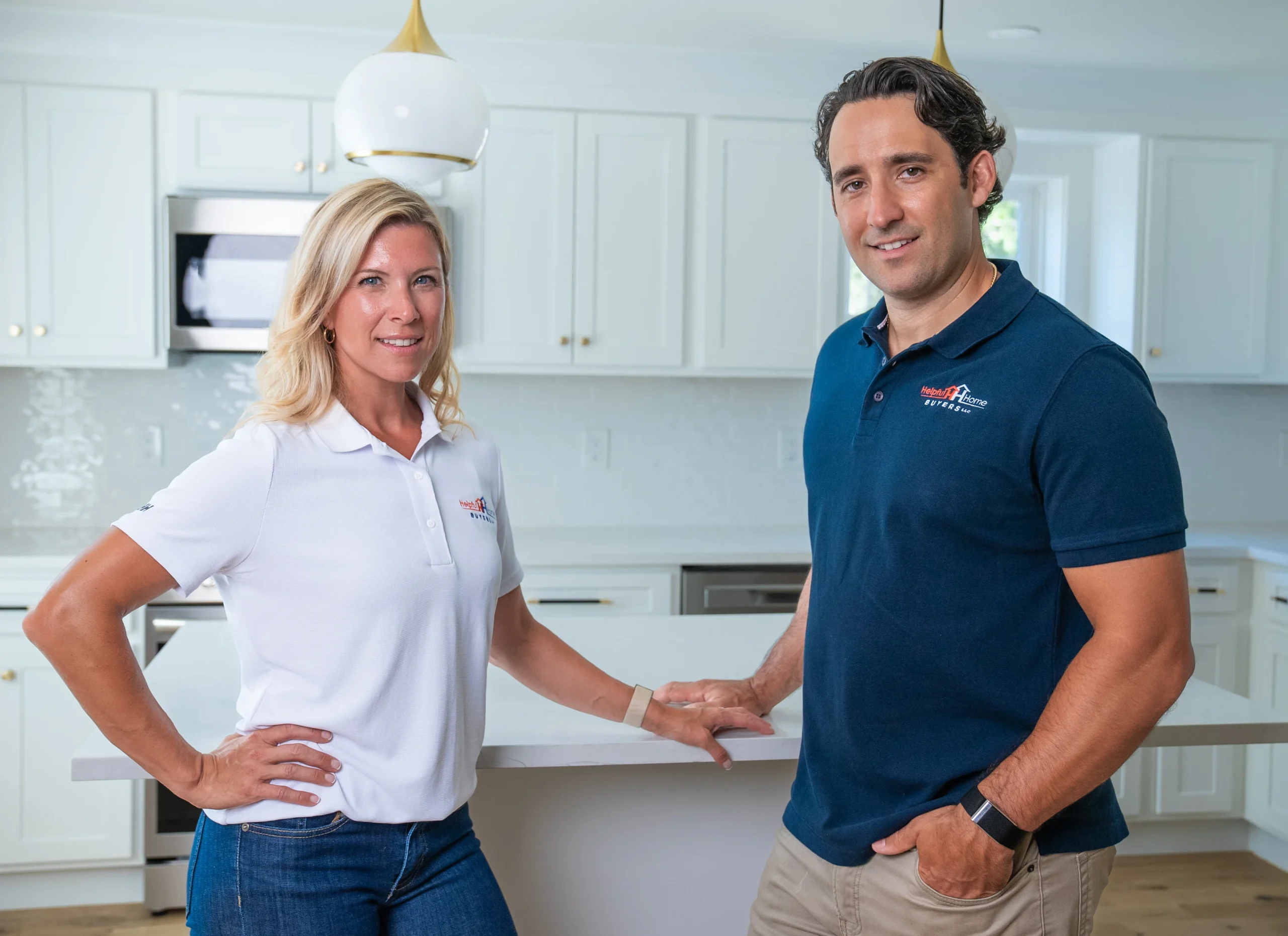 Megan And Dan of Helpful Home Buyers Megan And Dan Wearing branded Helpful Home Buyers polo shirts in a renovated kitchen